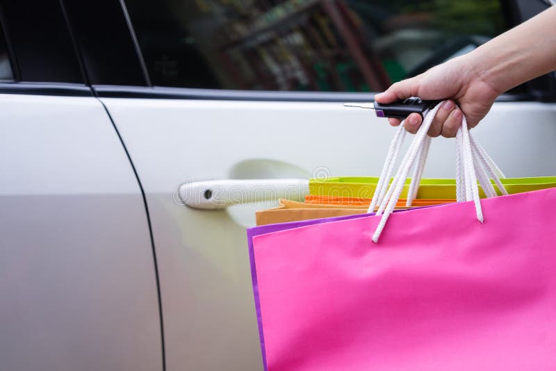 Mujer feliz con los bolsos de compras que abren el coche con la mano que lleva a cabo llave remota del coche Muchacha que presion fotografía de archivo Mujer feliz con los bolsos de compras que abren el coche con la mano que lleva a cabo llave remota del coche Muchacha que presion fotografía de archivo