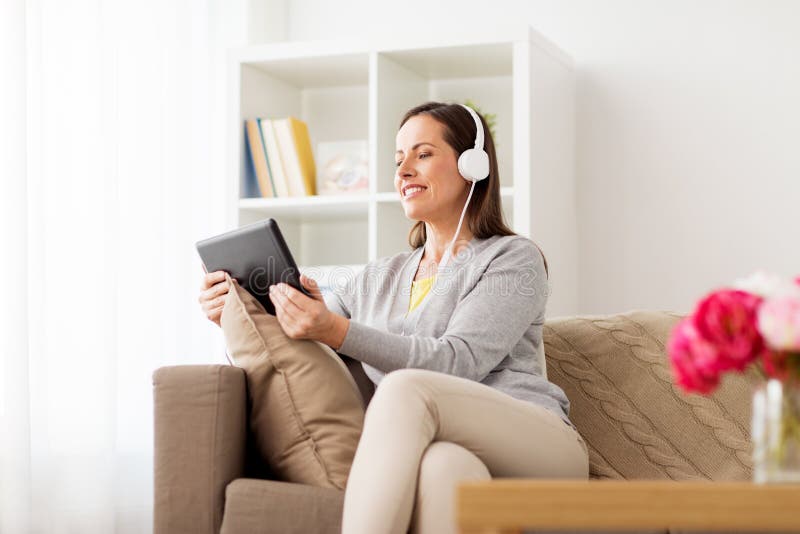Mujer feliz con PC y los auriculares de la tableta en casa