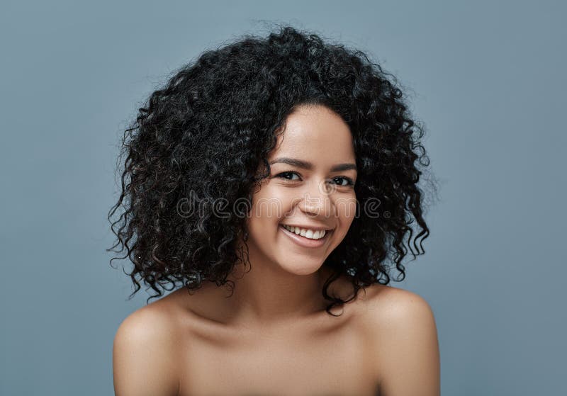 Mujer feliz con pelo rizado y piel limpia mirando la cámara imagen de archivo