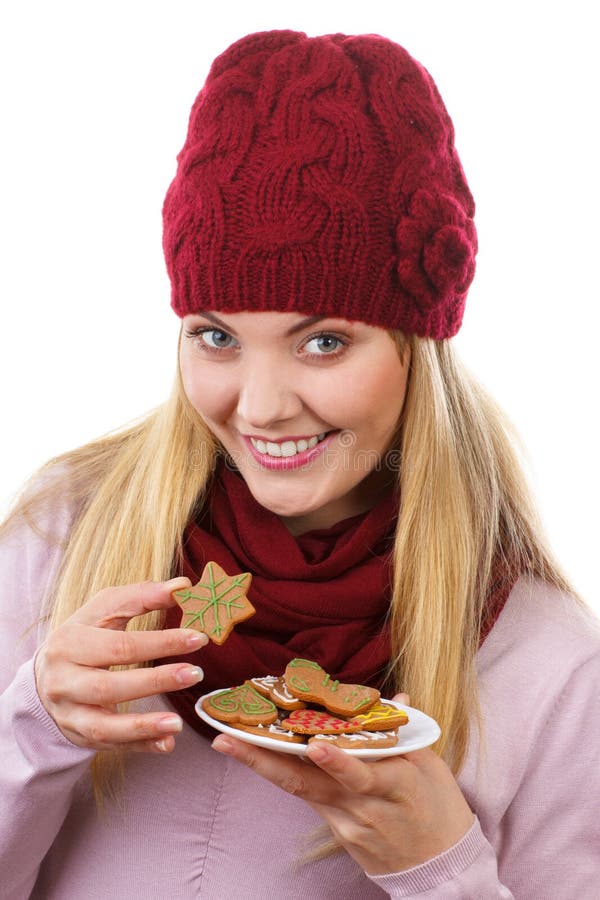 Mujer feliz en casquillo y mantón de lana que come las galletas del pan de jengibre, fondo blanco, tiempo de la Navidad fotos de archivo Mujer feliz en casquillo y mantón de lana que come las galletas del pan de jengibre, fondo blanco, tiempo de la Navidad fotos de archivo