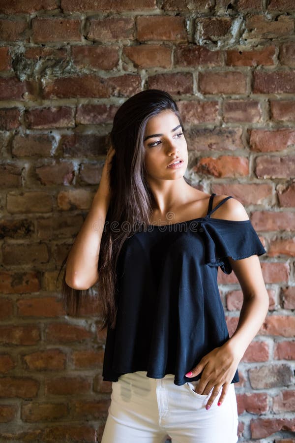 Mujer feliz hermosa joven en ropa casual contra la pared de ladrillo imagenes de archivo Mujer feliz hermosa joven en ropa casual contra la pared de ladrillo imagenes de archivo