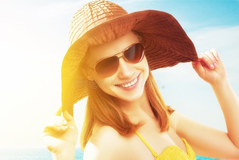 Una mujer con gafas de sol y un top amarillo se encuentra en una playa.