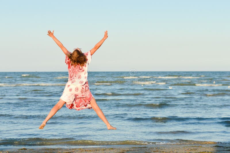 Mujer feliz joven que salta arriba en la playa fotos de archivo libres de regalías Mujer feliz joven que salta arriba en la playa fotos de archivo libres de regalías