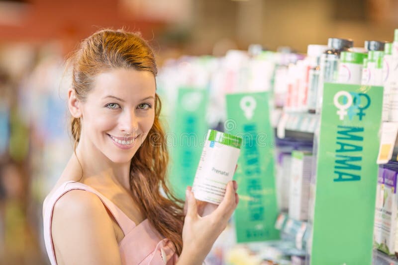 Mujer feliz que escoge suplementos diarios de la comida en una tienda foto de archivo libre de regalías Mujer feliz que escoge suplementos diarios de la comida en una tienda foto de archivo libre de regalías