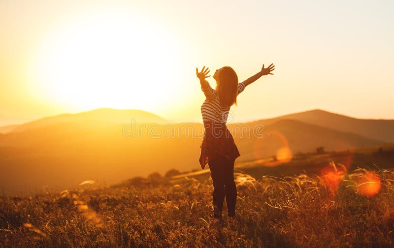 Mujer feliz que salta y que disfruta de vida en la puesta del sol en montañas fotografía de archivo libre de regalías