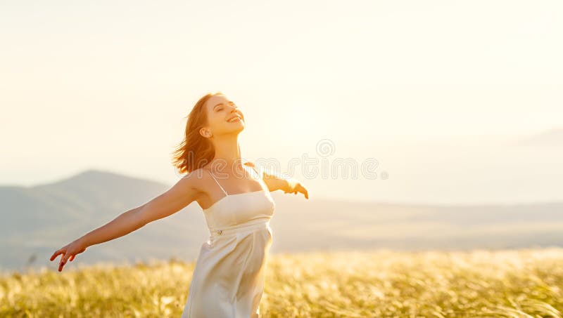 Mujer feliz que se coloca con ella detrás en puesta del sol en ope del iwith de la naturaleza imagen de archivo libre de regalías
