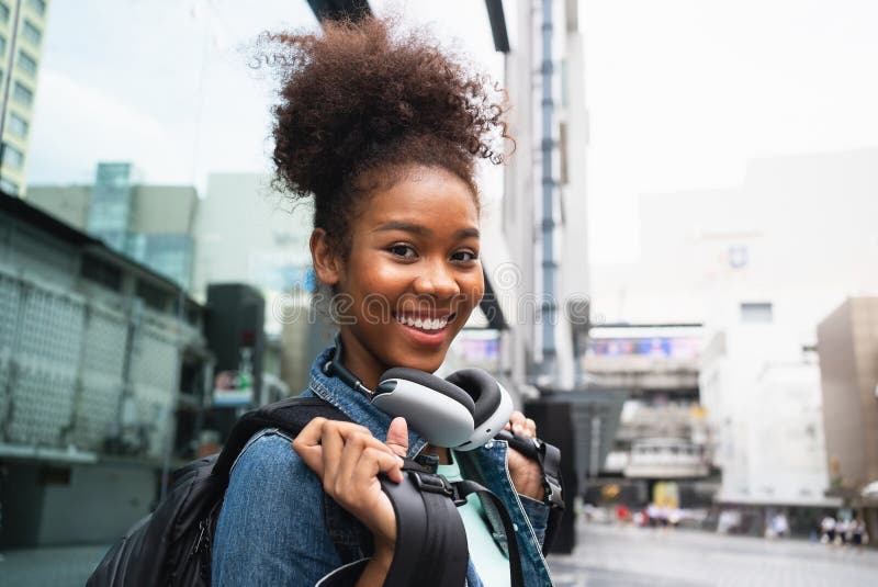 Mujer feliz sonriente caminando en la calle con mochila en la ciudad fotografía de archivo
