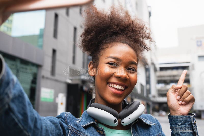 Mujer feliz sonriente caminando en la calle con mochila en la ciudad imagen de archivo libre de regalías