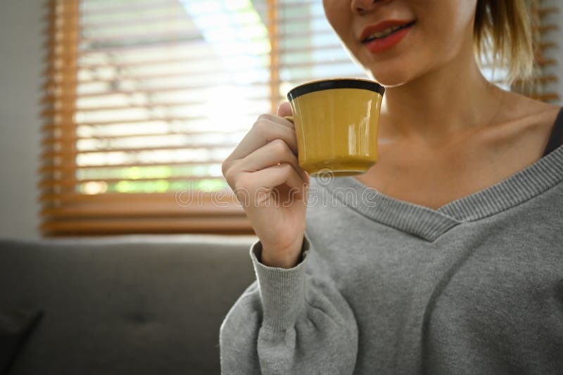 Mujer feliz tomando café caliente disfrutando del tiempo de calidad con las bebidas en casa imagen de archivo