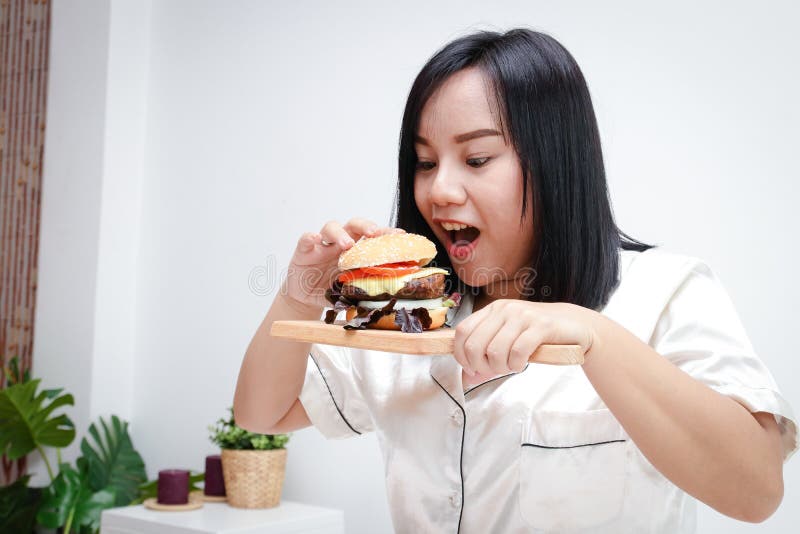 Mujer Gorda Acostada En La Cama Alcanzando Una Hamburguesa Vacía En La Mesa  Para Comer En La Cama. Concepto De Pérdida De Peso Fotos, retratos,  imágenes y fotografía de archivo libres de