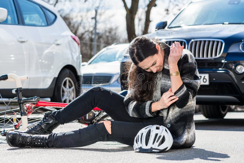 Mujer herida sentada en el suelo tras accidente de bicicleta imagenes de archivo