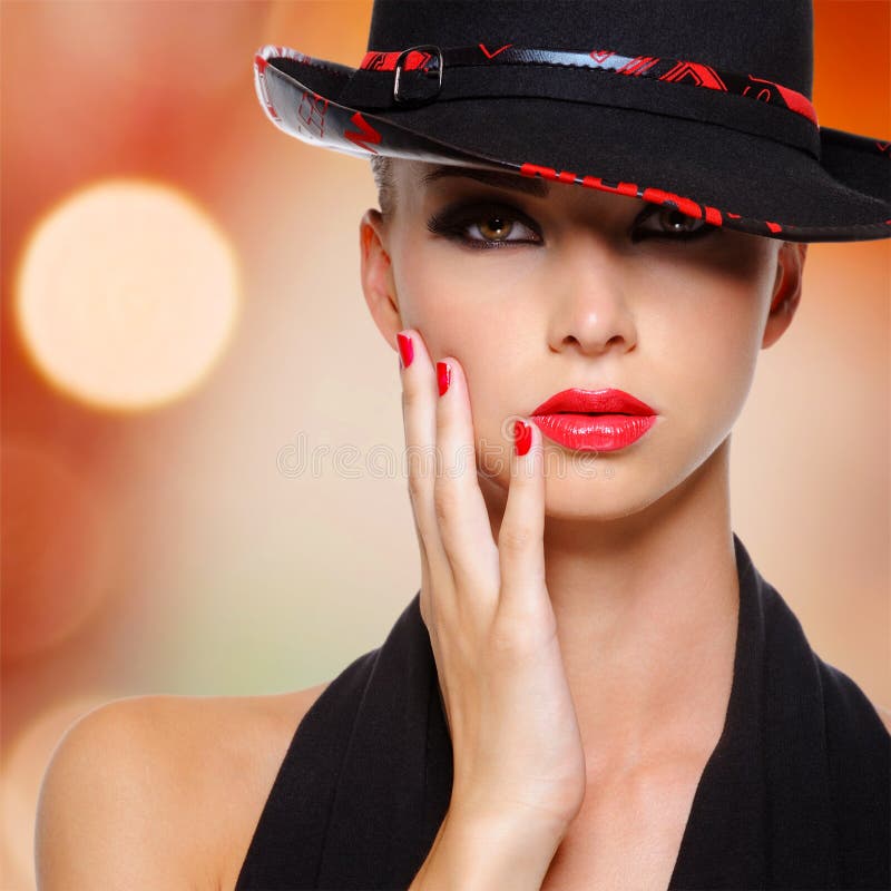 Mujer hermosa con los labios y los clavos rojos en sombrero negro fotografía de archivo libre de regalías Mujer hermosa con los labios y los clavos rojos en sombrero negro fotografía de archivo libre de regalías
