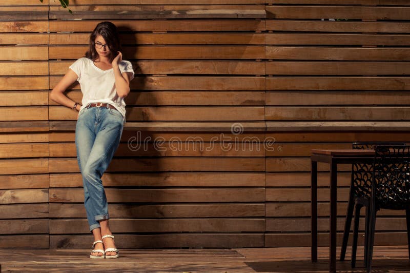 Mujer hermosa del inconformista que se inclina en la cerca de madera fotos de archivo libres de regalías Mujer hermosa del inconformista que se inclina en la cerca de madera fotos de archivo libres de regalías
