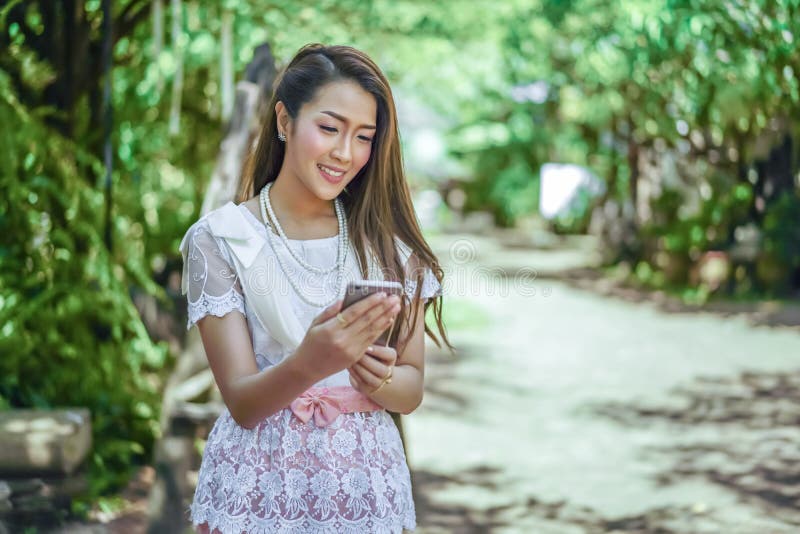 Mujer hermosa en vestido tradicional tailandés usando smartphone fotos de archivo Mujer hermosa en vestido tradicional tailandés usando smartphone fotos de archivo