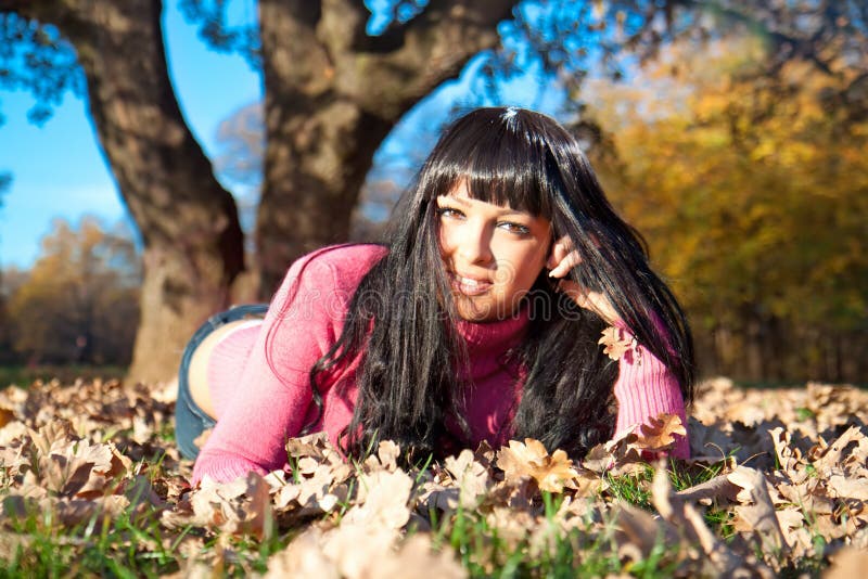 Mujer hermosa feliz que miente en el parque del otoño imagen de archivo libre de regalías Mujer hermosa feliz que miente en el parque del otoño imagen de archivo libre de regalías