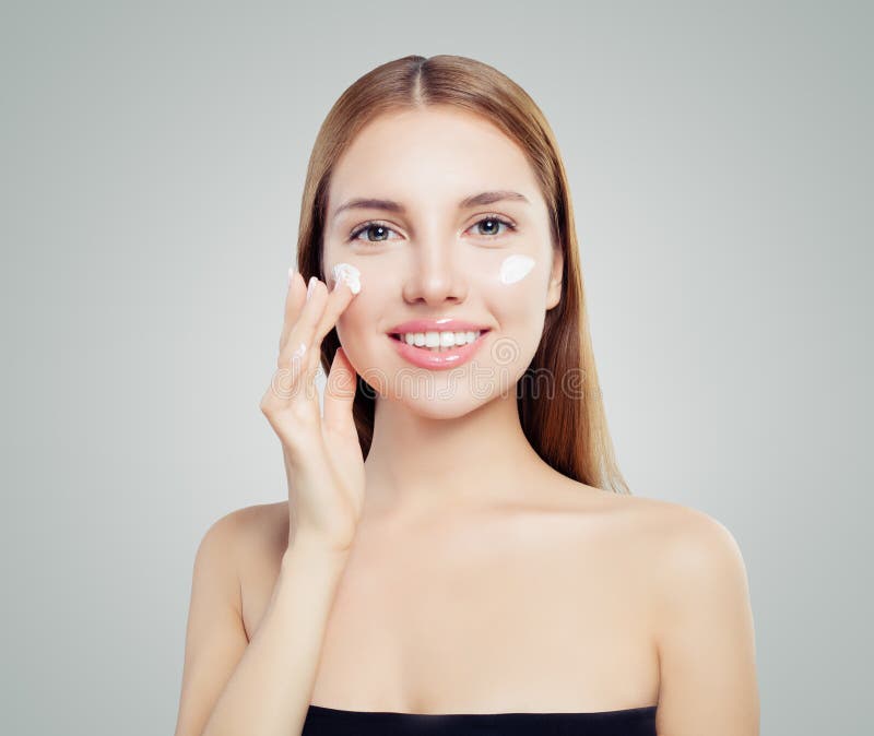 Mujer hermosa feliz que pone la crema en piel sana fotografía de archivo Mujer hermosa feliz que pone la crema en piel sana fotografía de archivo