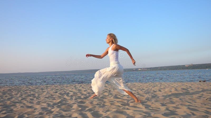 Mujer hermosa joven feliz que corre y que salta en la playa almacen de video