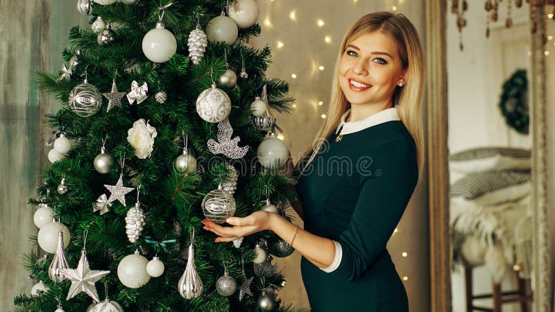 Mujer hermosa, joven que adorna un árbol de navidad fotografía de archivo Mujer hermosa, joven que adorna un árbol de navidad fotografía de archivo