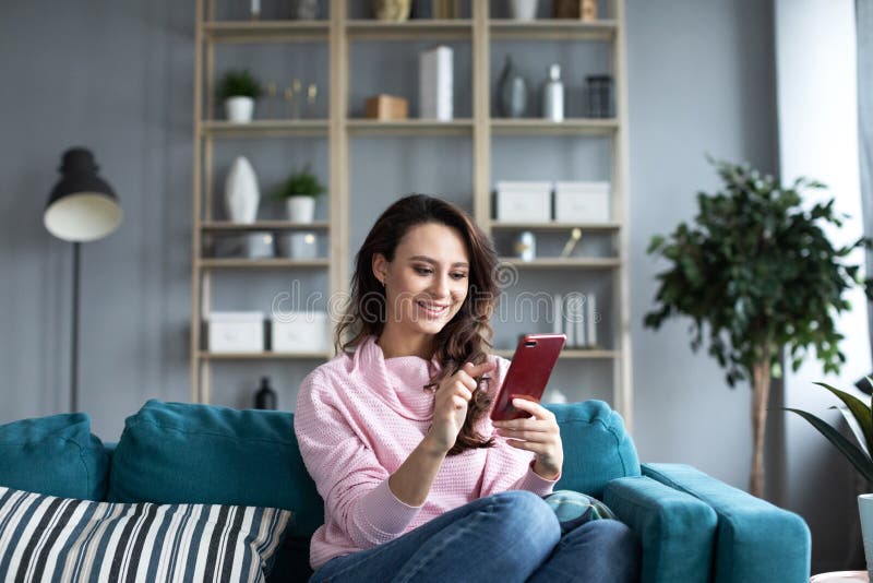 Mujer hermosa joven que usa smartphone en casa foto de archivo libre de regalías Mujer hermosa joven que usa smartphone en casa foto de archivo libre de regalías
