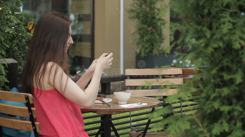 Mujer hermosa que hace el selfie, sentándose en café del verano al aire libre