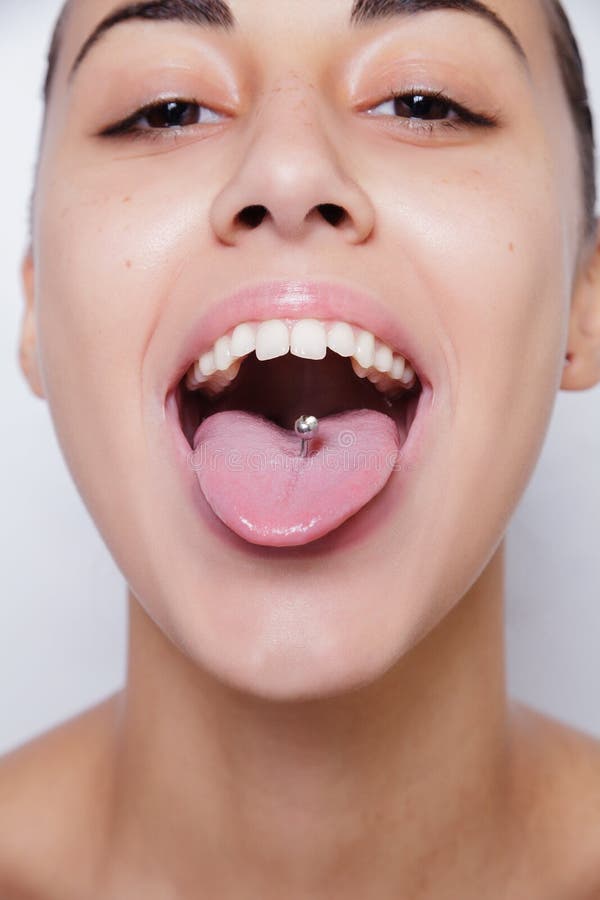 Mujer hermosa que se pega hacia fuera la lengua y que muestra la perforación joven imagen de archivo Mujer hermosa que se pega hacia fuera la lengua y que muestra la perforación joven imagen de archivo