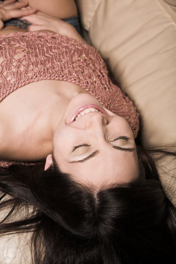 Mujer hermosa que se relaja en un sofá blanco fotografía de archivo libre de regalías Mujer hermosa que se relaja en un sofá blanco fotografía de archivo libre de regalías