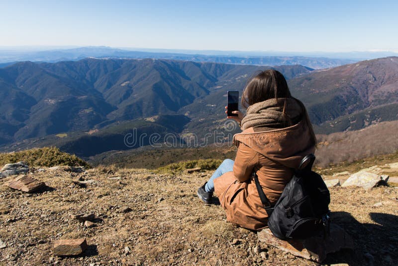 Mujer hermosa que se sienta después de caminar y de tomar la foto con el teléfono durante invierno u otoño en Cataluña fotografía de archivo Mujer hermosa que se sienta después de caminar y de tomar la foto con el teléfono durante invierno u otoño en Cataluña fotografía de archivo