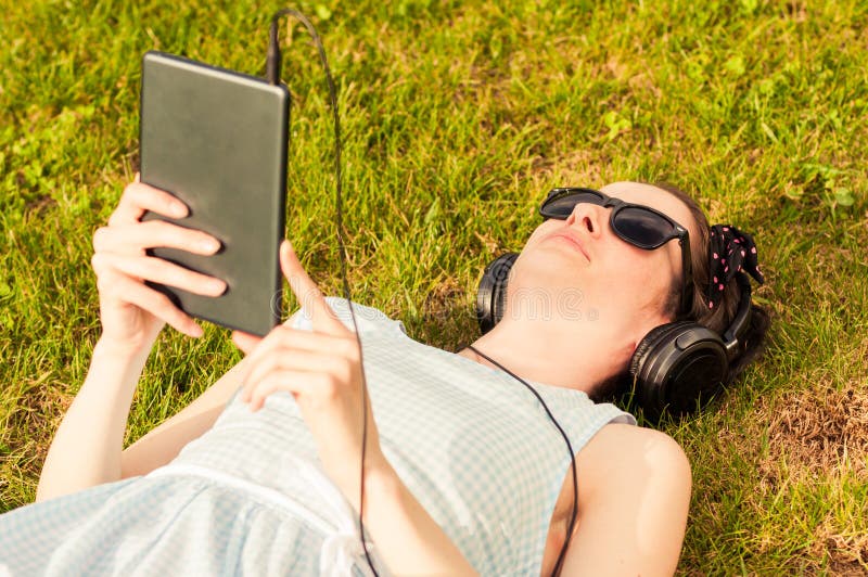 Mujer hermosa que sostiene la tableta digital en parque el día soleado imagenes de archivo Mujer hermosa que sostiene la tableta digital en parque el día soleado imagenes de archivo