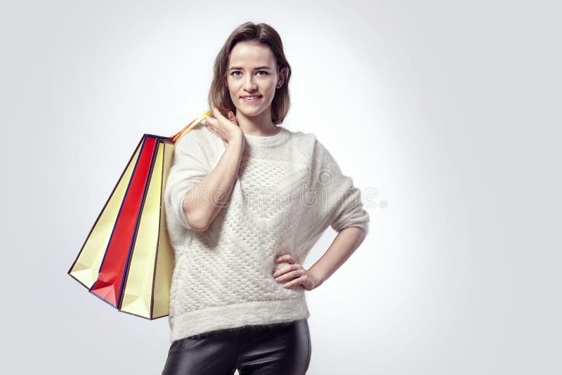Mujer hermosa rubia con las bolsas de papel de las compras en hombro Emociones tranquilas, cara caucásica, suéter imagenes de archivo Mujer hermosa rubia con las bolsas de papel de las compras en hombro Emociones tranquilas, cara caucásica, suéter imagenes de archivo