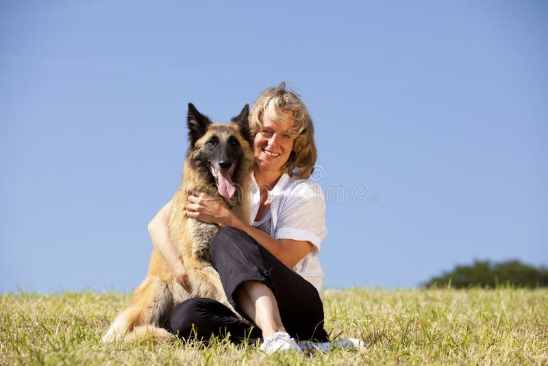 Mujer hermosa sonriente que abraza su perro imagenes de archivo Mujer hermosa sonriente que abraza su perro imagenes de archivo