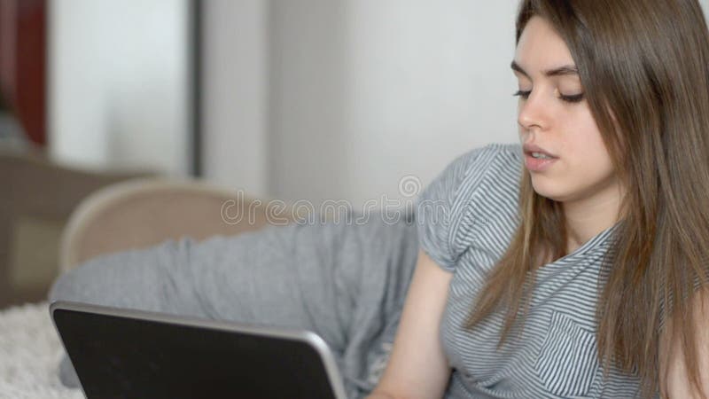 Mujer hermosa sonriente que trabaja en el ordenador portátil en cama