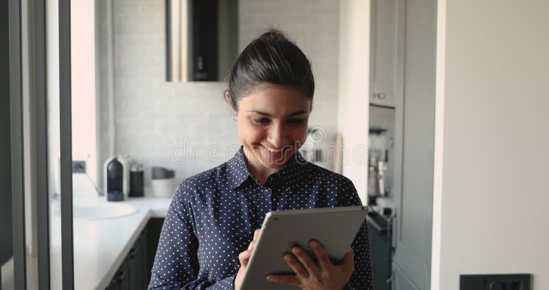 Mujer india envía mensajes de texto usando el dispositivo tablet sonrisas mirando la cámara