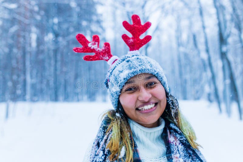 Mujer india feliz divirtiéndose y disfrutando de la primera nieve usando divertido sombrero cuerno de ciervo fotos de archivo libres de regalías
