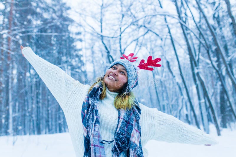 Mujer india feliz divirtiéndose y disfrutando de la primera nieve usando divertido sombrero cuerno de ciervo fotos de archivo