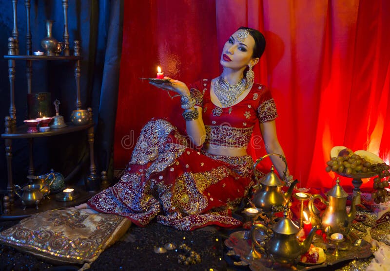 Mujer india joven hermosa en ropa tradicional de la sari y joyería oriental con la vela foto de archivo libre de regalías Mujer india joven hermosa en ropa tradicional de la sari y joyería oriental con la vela foto de archivo libre de regalías