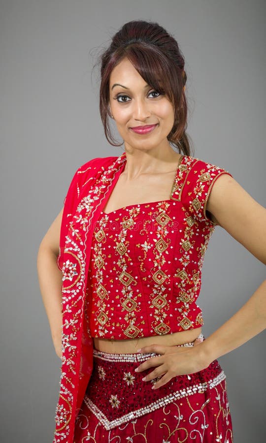 Mujer india joven que se coloca con sus brazos en jarras