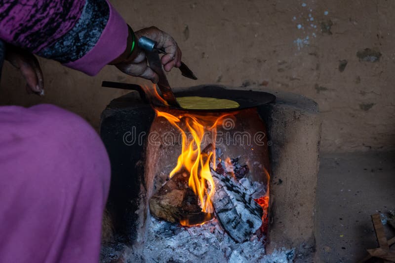Mujer india que hace Roti en chulha tradicional de la estufa bajo condiciones duras imagen de archivo Mujer india que hace Roti en chulha tradicional de la estufa bajo condiciones duras imagen de archivo