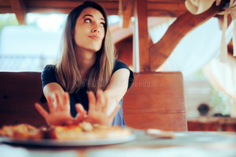 Mujer infeliz que se niega a comer su plato de pizza en un restaurante