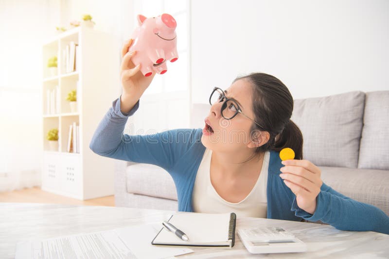 Mujer infeliz que vacia su piggybank foto de archivo libre de regalías Mujer infeliz que vacia su piggybank foto de archivo libre de regalías