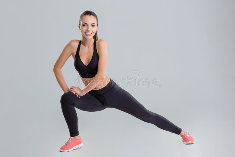 Mujer joven activa positiva de la aptitud que calienta y que estira foto de archivo Mujer joven activa positiva de la aptitud que calienta y que estira foto de archivo