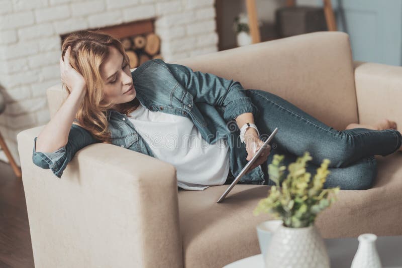 Mujer joven agradable que lee el libro electrónico imágenes de archivo libres de regalías