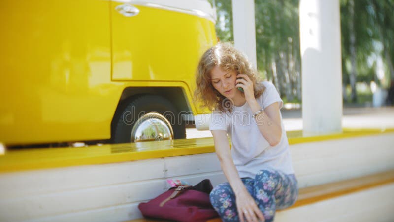 Mujer joven al aire libre por música que escucha del coche amarillo del carro en auriculares usando el smartphone - relajación, g