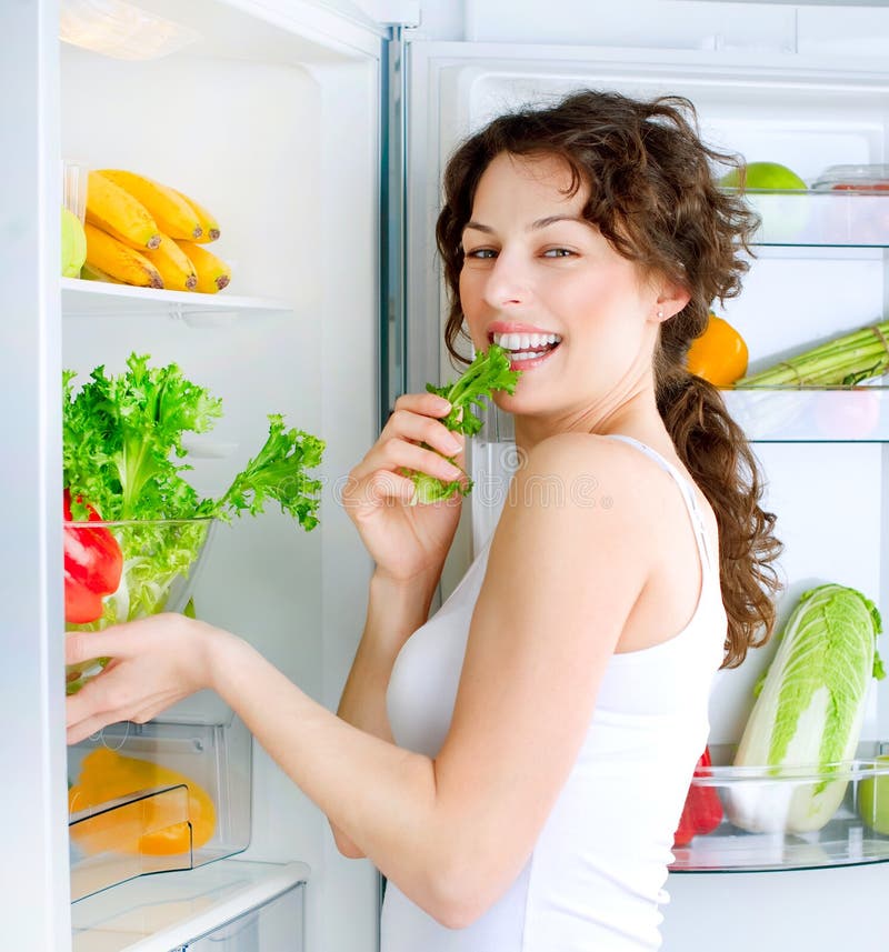 Mujer joven cerca del refrigerador foto de archivo Mujer joven cerca del refrigerador foto de archivo