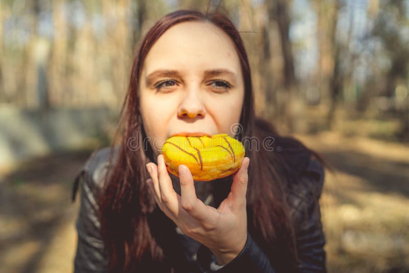 Mujer joven comiendo anacardos en los bosques Brunette jóven casual en la chaqueta sentada en el tronco en los bosques y comiendo fotografía de archivo libre de regalías