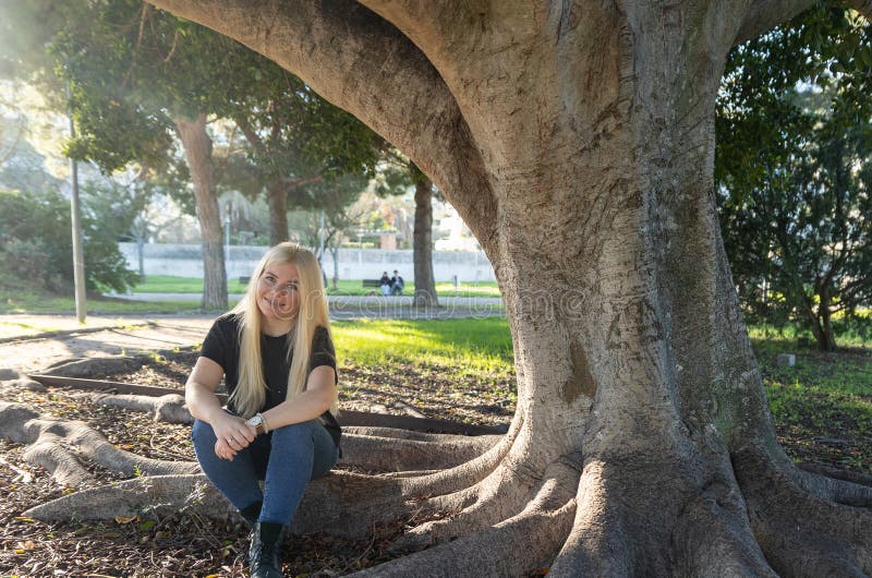 Mujer joven con cordones sonriendo bajo el árbol en el parque fotografía de archivo