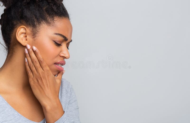 Mujer joven con dolor agudo de muelas, sosteniendo su mandíbula