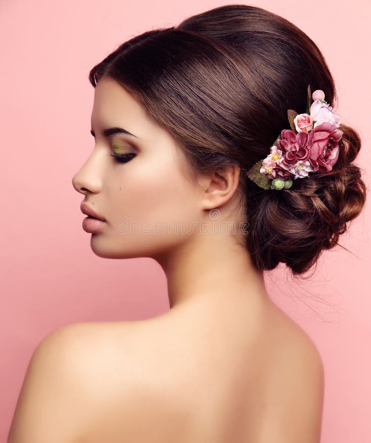 Mujer joven con el peinado elegante y flores accesorias