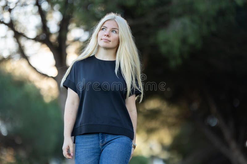 Mujer joven con el pelo rubio parado en el parque fotografía de archivo