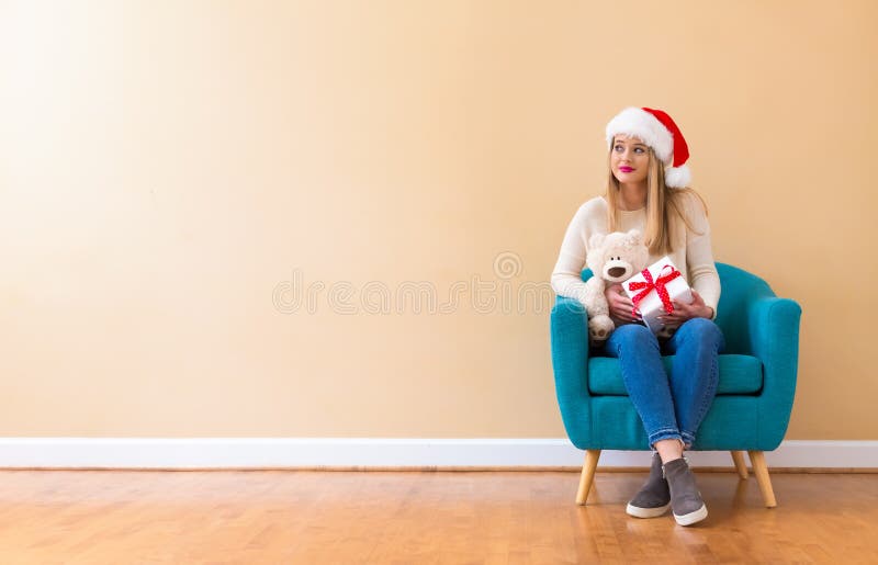 Mujer joven con el sombrero de santa que sostiene un oso de peluche imágenes de archivo libres de regalías Mujer joven con el sombrero de santa que sostiene un oso de peluche imágenes de archivo libres de regalías