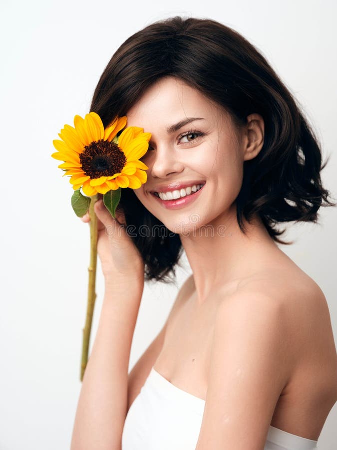 Mujer joven con girasol sonriendo y mirando la cámara aislada en el fondo blanco fotos de archivo libres de regalías